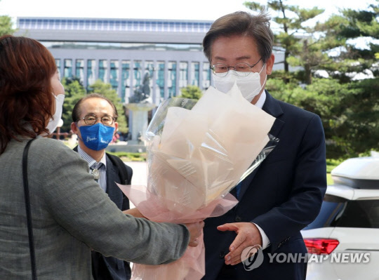 이재명 더불어민주당 의원이 7일 오전 국회 의원회관에 첫출근하며 지지자로부터 꽃다발을 받고 있다.<연합뉴스>